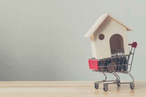 Pennies and a toy house in a cart representing the help you can get from a mortgage broker