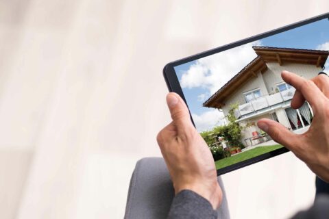 A person zooms in on an ipad with an image of a house for a virtual viewings