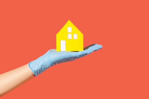 A hand with a medical glove holds a house to represent Home Viewing Safety Tips