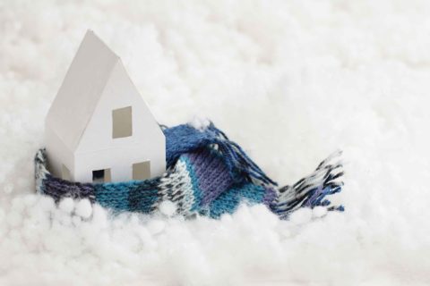 A toy house in a scarf representing selling your home in winter