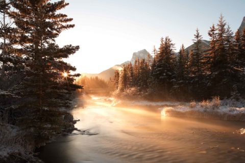 A walking bridge on the south side of Canmore in the early winter with steam and a frosty sunrise