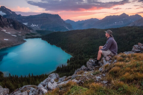 A person sits on the grass overlooking a lake in the Bow Valley