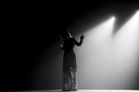 A woman under stage lights from Banff Theatre Collective