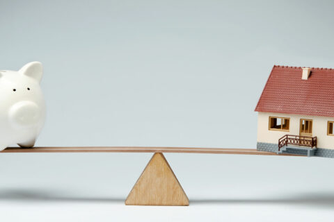 Piggy bank and house on a see saw to represent mortgage rates