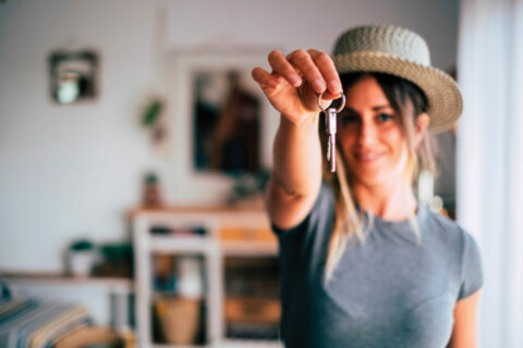 A woman holds up a key to represent buying a home on your own