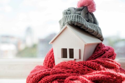 A house wrapped in a scarf and a toque represents time to winterize your home