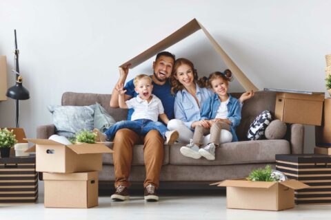 Family sitting on a couch under a cardboard roof to represent an alternative lender